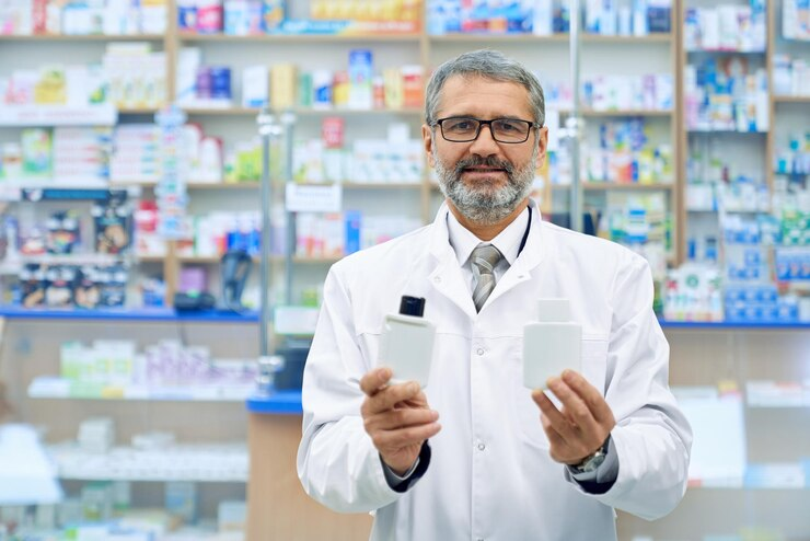 A pharmacist is facing the camera and showing two different pharma products in a pharma hypermarket full of pharma products. - By Smotec Pharmaceuticals (PCD Pharma Company in Arunachal Pradesh) https://smotecpharma.com/