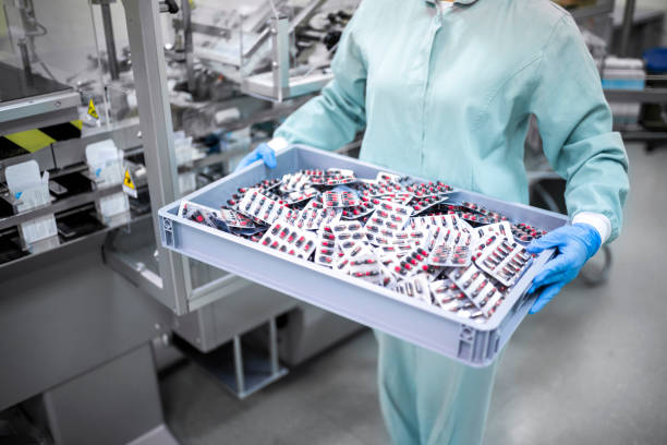 A lab technician carrying packed capsules in a big tray from a pharma manufacturing unit. - By Smotec Pharmaceutiucals (Best PCD Pharma Company in Meghalaya ) https://smotecpharma.com/